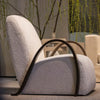 Contemporary armchair with textured white upholstery and curved wood armrests.