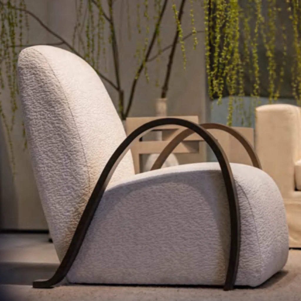 Contemporary armchair with textured white upholstery and curved wood armrests.
