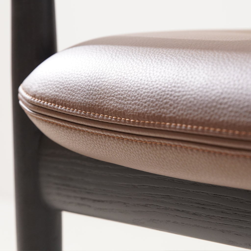 Close-up of brown leather upholstered padded seat on Brody Dining Chair