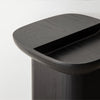 Contemporary black ashwood side table featuring smooth curves and a sculptural pedestal base