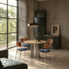 CRUX and PORTO 4-seater round dining set with blue cushioned chairs in a modern industrial-style dining room