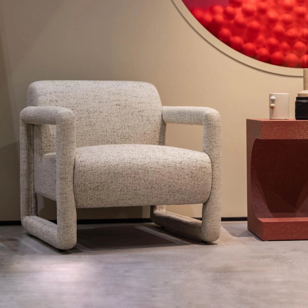 Modern armchair featuring textured white fabric upholstery and geometric wooden armrests in cozy lounge area.