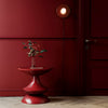 Unique and elegant round top side table in deep maroon red made from fiberglass