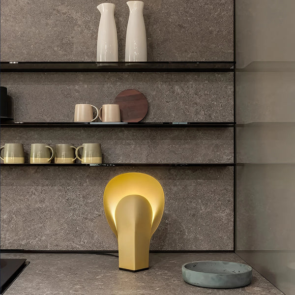 Nodo table lamp in matte gold steel, warm lighting in a contemporary kitchen setting.