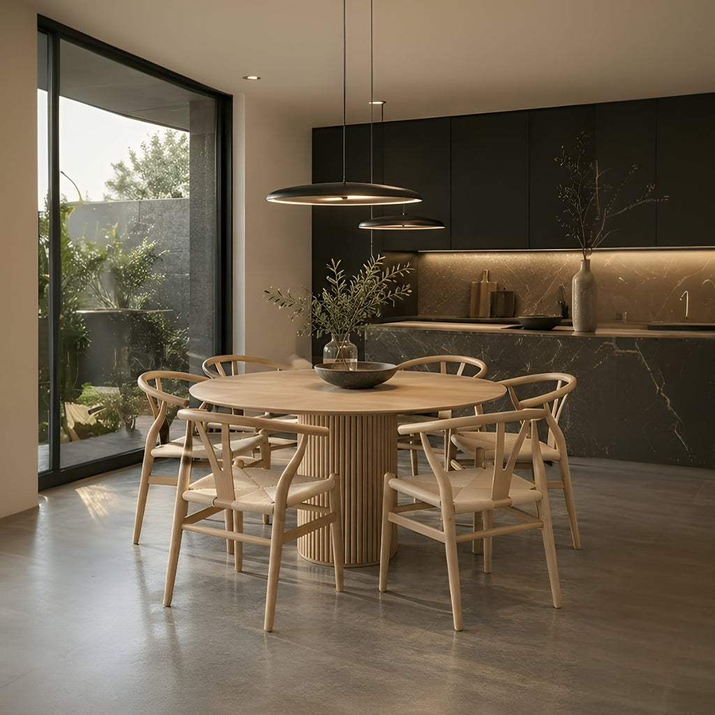 Six-seater RONAN round wood dining table with FISKBEIN woven seat chairs in a modern dark kitchen dining space.