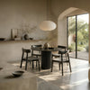 RONAN and IRIGUCHI four-seater black round dining set in a warm minimalist dining room with neutral walls.